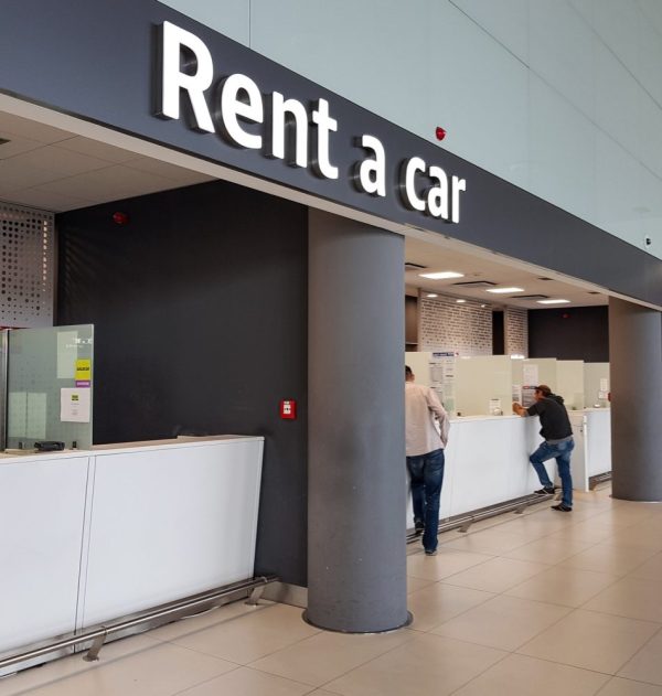 people standing at a counter of rent a car shop