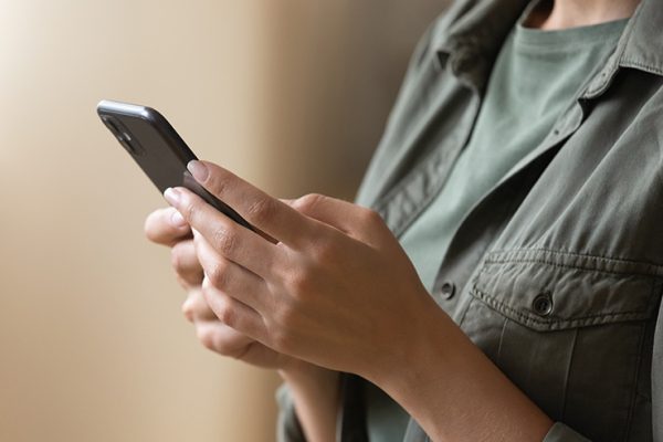 Casual young female hands holding using modern smartphone device indoors