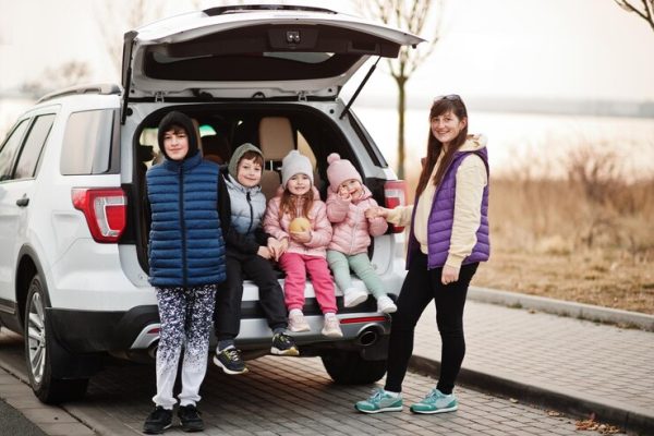 mother-with-four-kids-sitting-trunk-big-suv-car_627829-1516